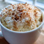 Coconut almond mug cake served warm in a mug with toasted coconut topping