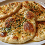 stack of golden garlic naan on a wooden board